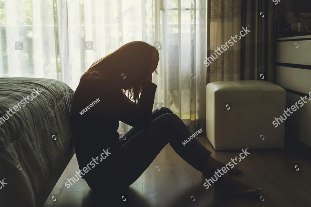 A woman sitting on the floor with her head in her hands