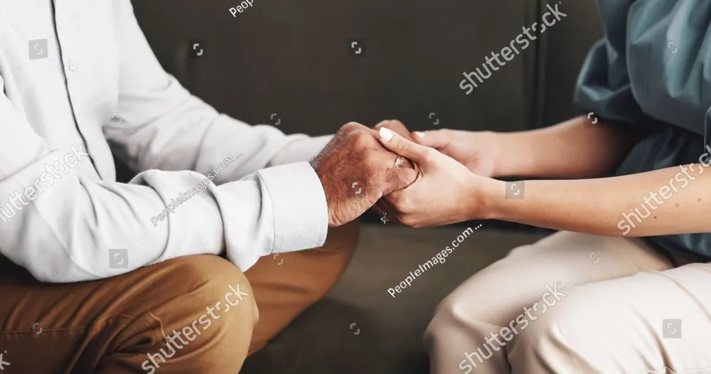 One person holding another person's hands in comfort