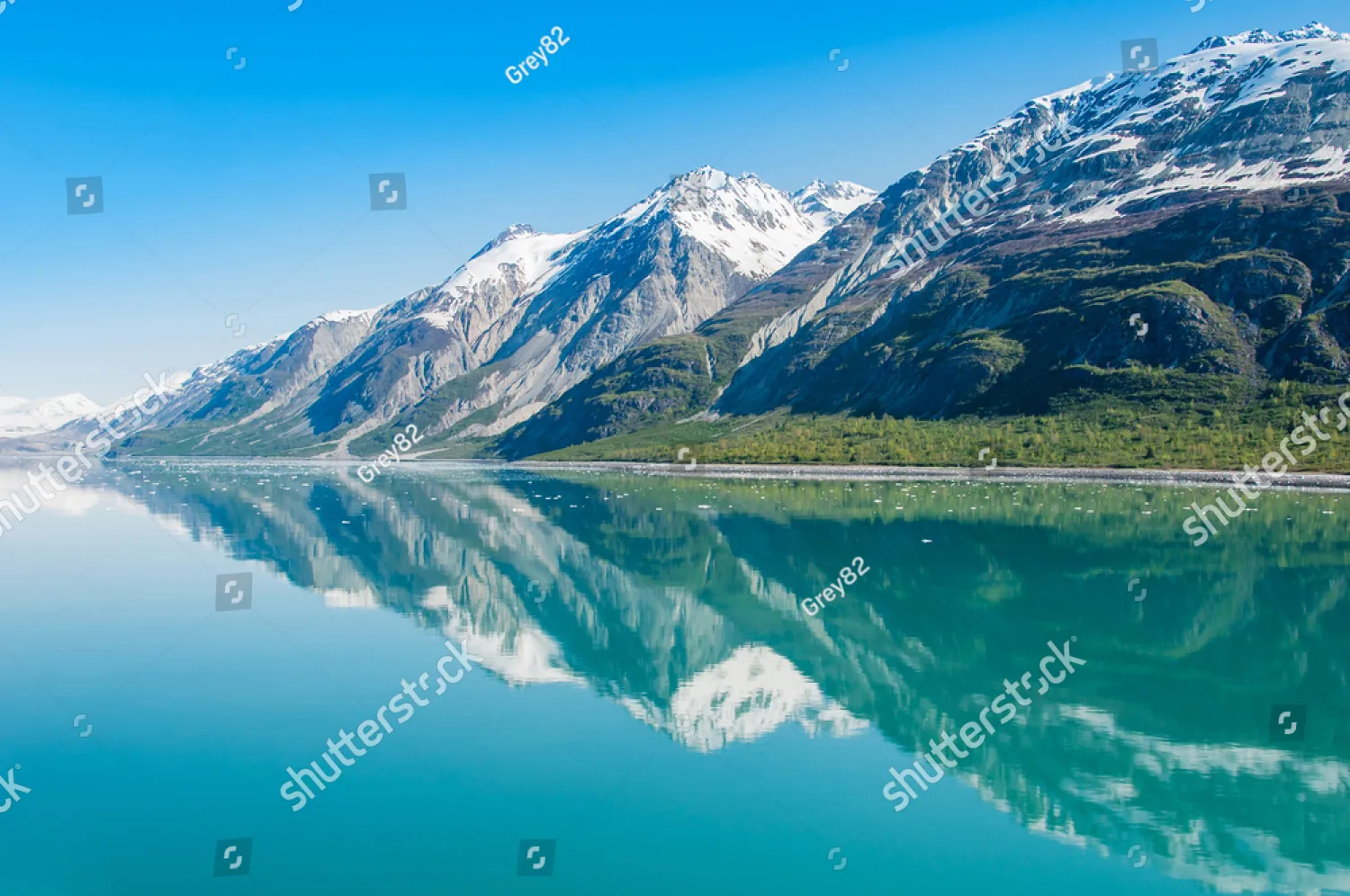 Snow-capped mountains mirrored in a still turquoise lake