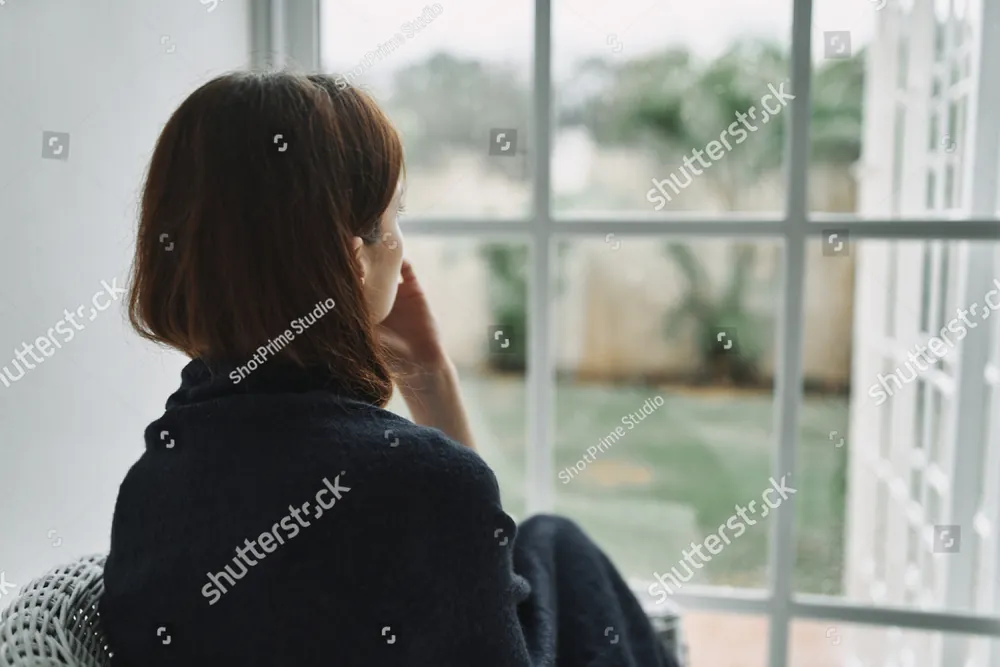A woman wrapped in a blanket looking out a window
