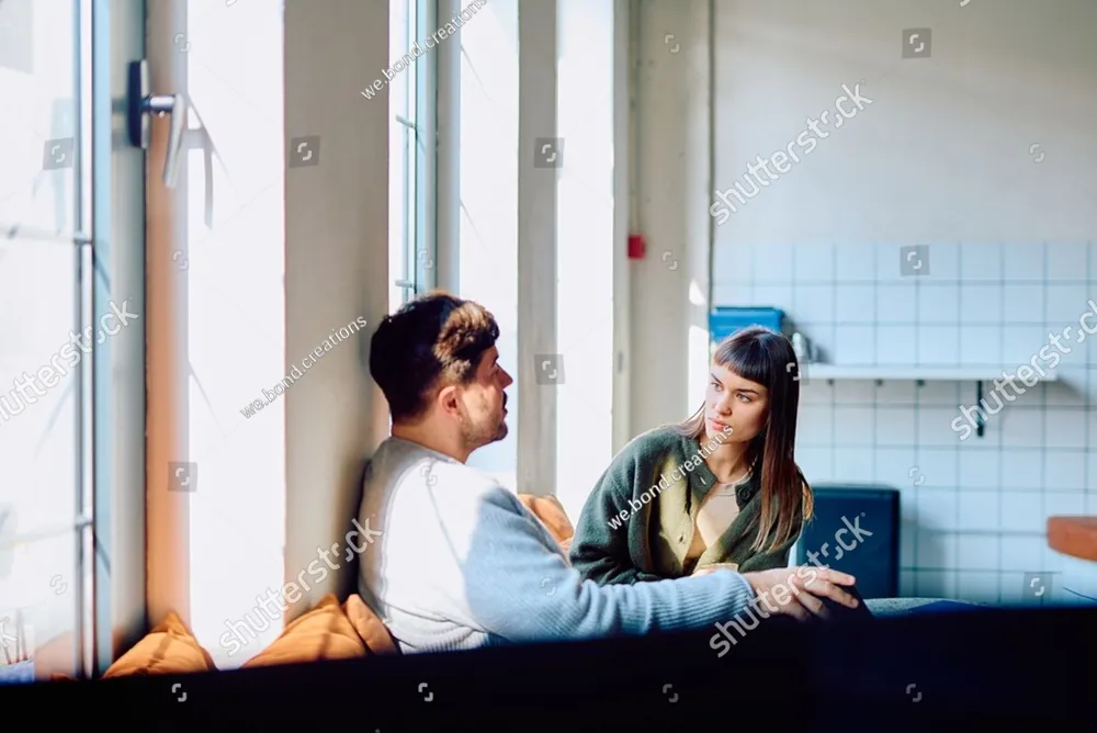 A couple talking on a window seat at home