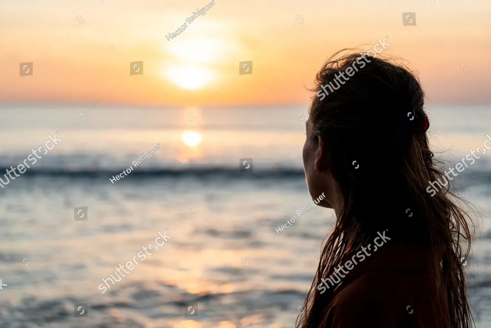 A woman looking out over the sea at sunrise